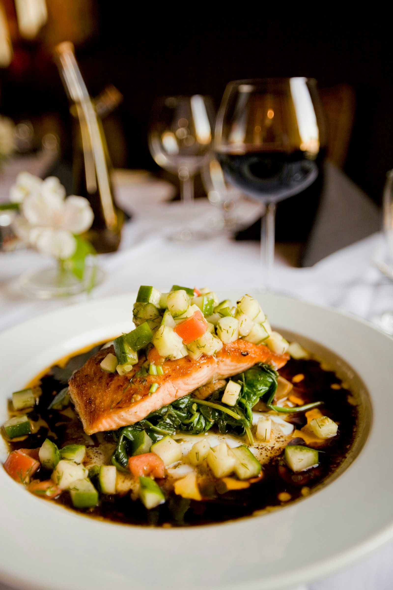 A pan-seared salmon fillet on a white plate next to roasted asparagus spears and a lemon wedge.